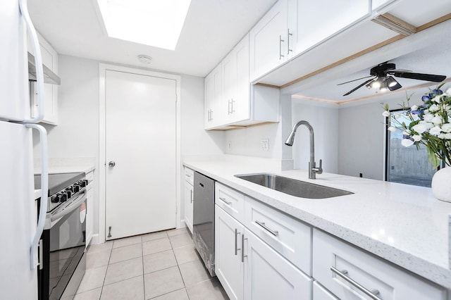 kitchen featuring a ceiling fan, light tile patterned flooring, a sink, stainless steel appliances, and white cabinets