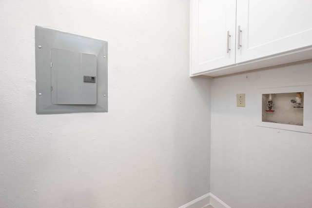 clothes washing area featuring electric panel, baseboards, cabinet space, and washer hookup