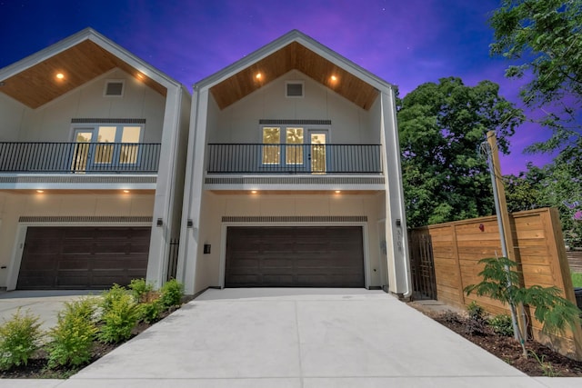 view of front of house with a balcony, an attached garage, fence, and driveway