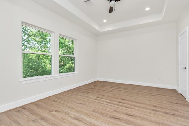 empty room with visible vents, a raised ceiling, and baseboards