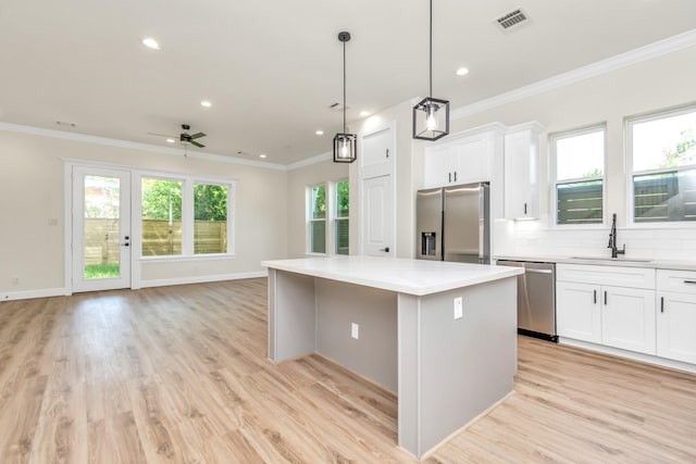 kitchen with a kitchen island, open floor plan, ornamental molding, stainless steel appliances, and a sink