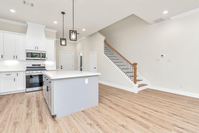 kitchen featuring stainless steel appliances, a kitchen island, visible vents, and light wood-style flooring