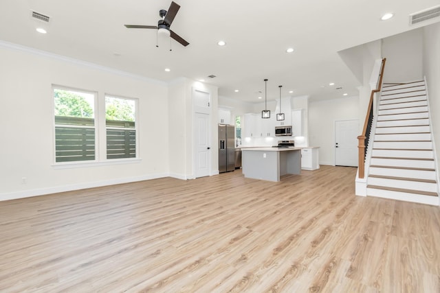 unfurnished living room with visible vents, baseboards, light wood-style floors, and stairs