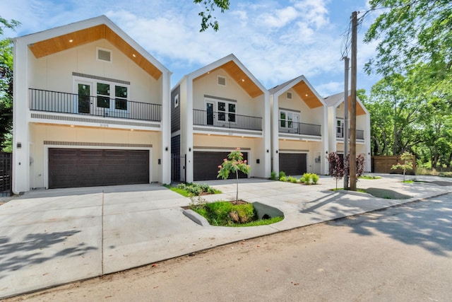 view of front of property featuring stucco siding, driveway, french doors, a garage, and a balcony