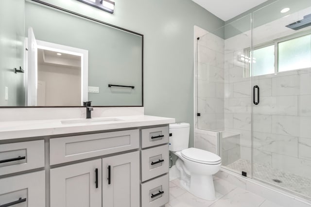 bathroom featuring toilet, marble finish floor, a stall shower, and vanity