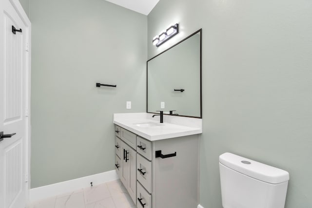 half bath with baseboards, toilet, marble finish floor, and vanity