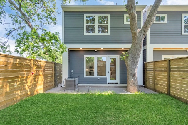 rear view of property featuring cooling unit, a yard, and a fenced backyard