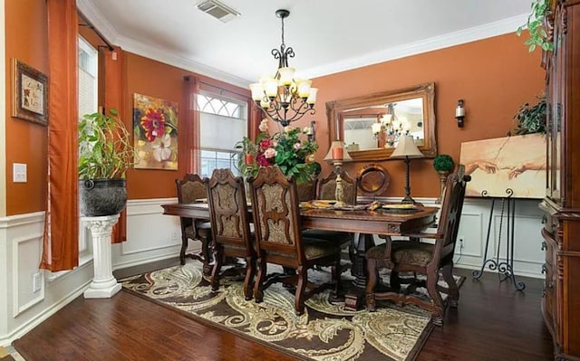 dining room featuring visible vents, ornamental molding, dark wood-type flooring, wainscoting, and a notable chandelier