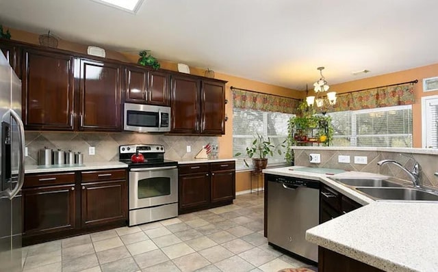 kitchen with pendant lighting, light countertops, decorative backsplash, stainless steel appliances, and a sink