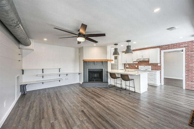 unfurnished living room with a brick fireplace, a ceiling fan, and dark wood-style flooring