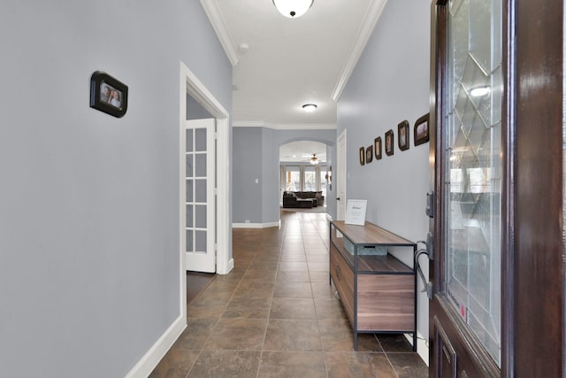 hall featuring crown molding, baseboards, french doors, arched walkways, and dark tile patterned flooring