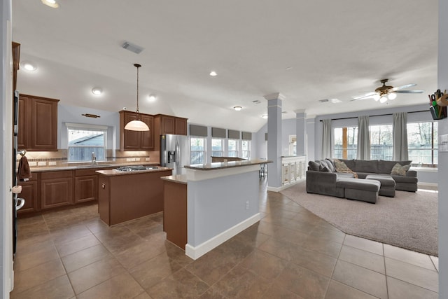 kitchen with lofted ceiling, a sink, appliances with stainless steel finishes, tasteful backsplash, and a center island