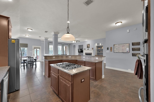 kitchen featuring visible vents, a ceiling fan, open floor plan, a center island, and stainless steel appliances