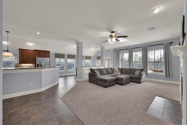 living area with dark tile patterned floors, visible vents, a wealth of natural light, and ceiling fan