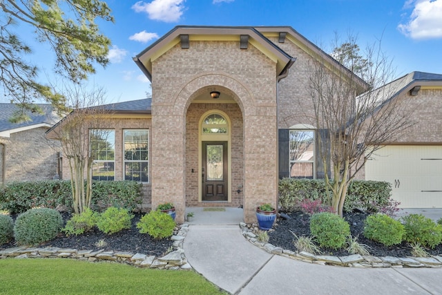 doorway to property featuring brick siding and a garage