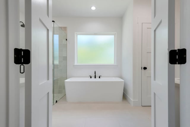 bathroom featuring recessed lighting, a freestanding tub, a shower stall, and tile patterned flooring