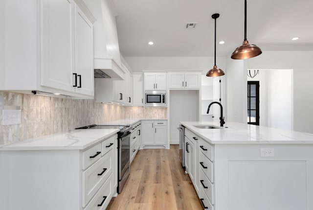 kitchen with visible vents, an island with sink, decorative backsplash, stainless steel appliances, and a sink