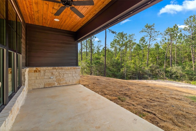 view of patio / terrace featuring a ceiling fan and a forest view