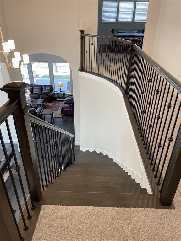 stairs featuring arched walkways, a towering ceiling, and wood finished floors