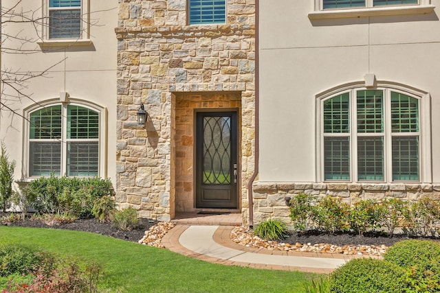 property entrance featuring stucco siding and stone siding