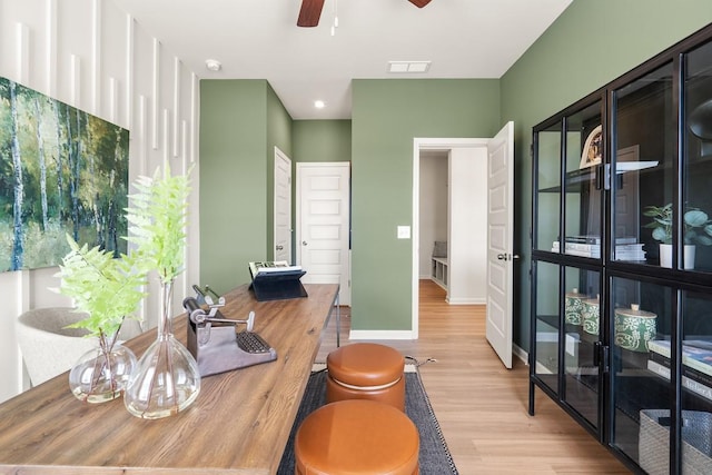 office featuring light wood finished floors, visible vents, ceiling fan, and baseboards