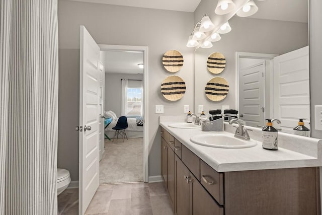 ensuite bathroom featuring double vanity, toilet, ensuite bathroom, and a sink