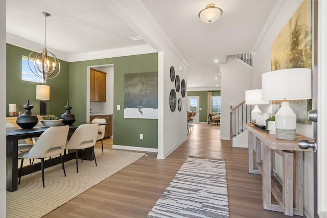 foyer featuring an inviting chandelier, light wood-style flooring, stairs, and crown molding