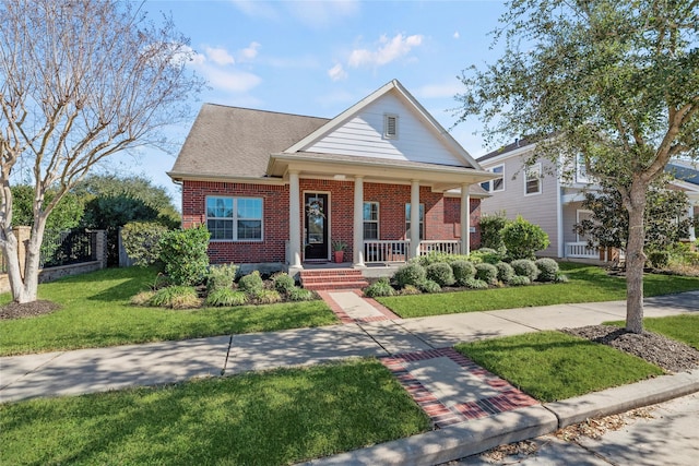 greek revival house featuring brick siding, covered porch, and a front lawn