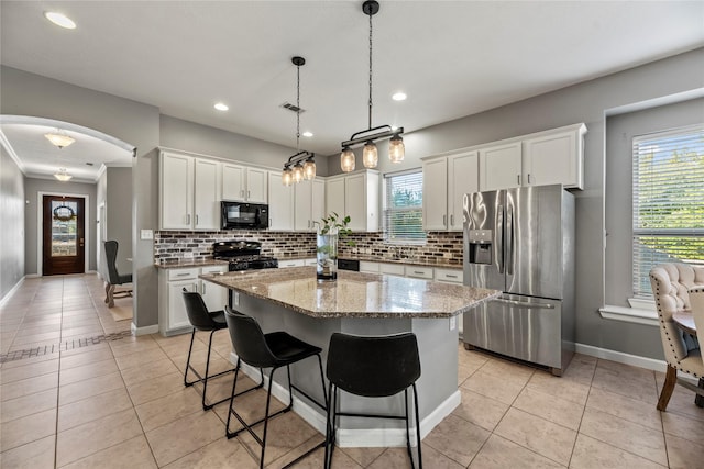 kitchen featuring light tile patterned floors, decorative backsplash, arched walkways, and black appliances