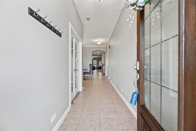 corridor with ornamental molding, french doors, arched walkways, light tile patterned floors, and baseboards