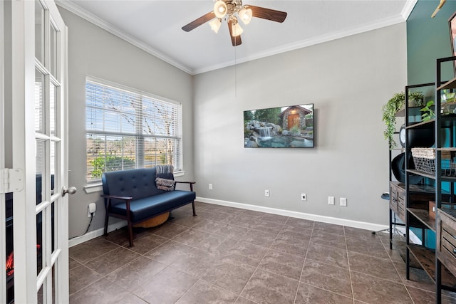 living area featuring crown molding, dark tile patterned flooring, a ceiling fan, and baseboards