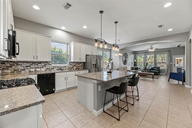 kitchen with visible vents, a kitchen island, black appliances, open floor plan, and backsplash