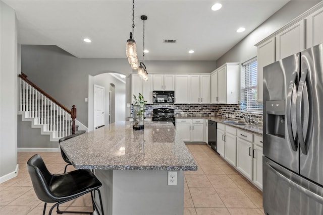 kitchen featuring black appliances, light tile patterned floors, tasteful backsplash, and a kitchen island