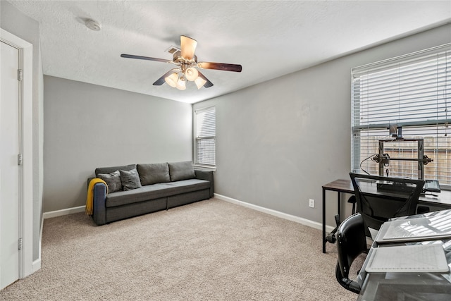 carpeted office space with baseboards, a textured ceiling, and a ceiling fan