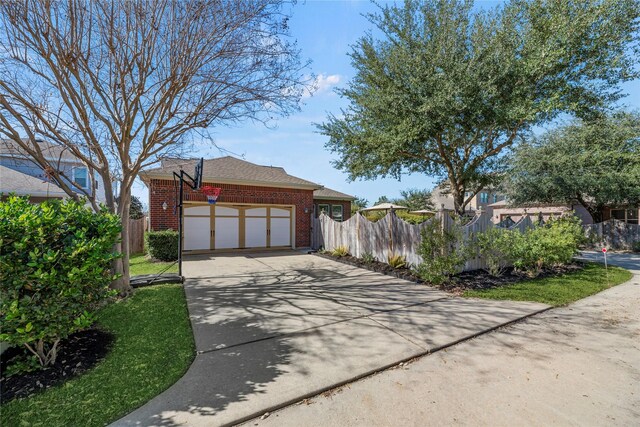 view of side of home with a garage, fence, brick siding, and driveway