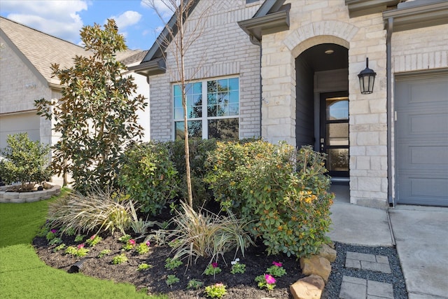 doorway to property with stone siding, brick siding, and an attached garage