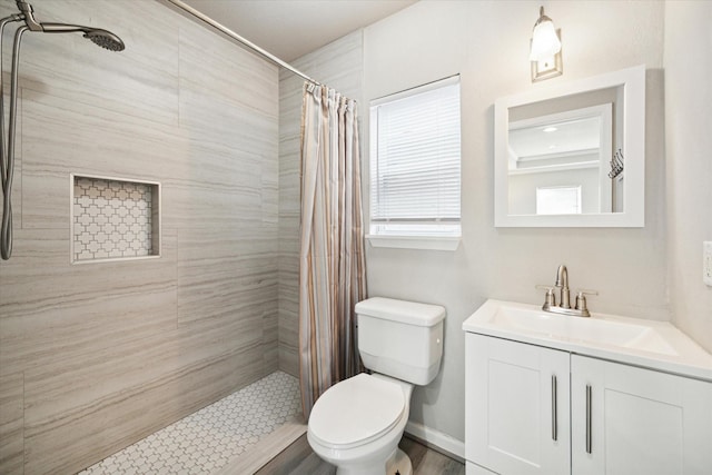 bathroom featuring baseboards, toilet, vanity, and a tile shower