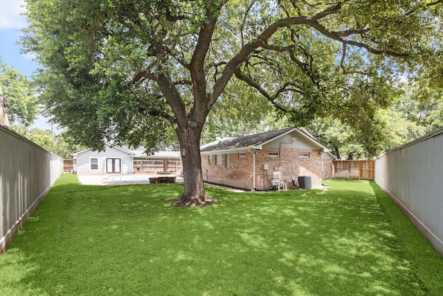 view of yard featuring an outbuilding, central AC unit, and a fenced backyard