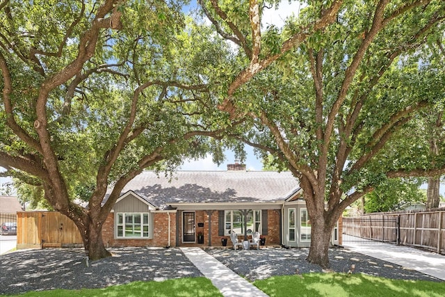 single story home featuring brick siding, a shingled roof, a chimney, and fence