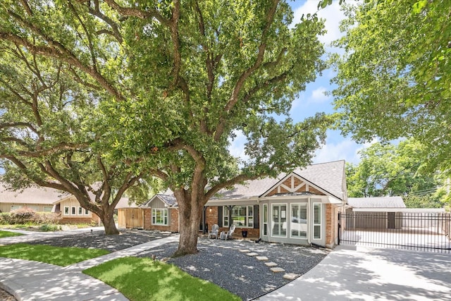 view of front of property featuring french doors, concrete driveway, fence, and a gate