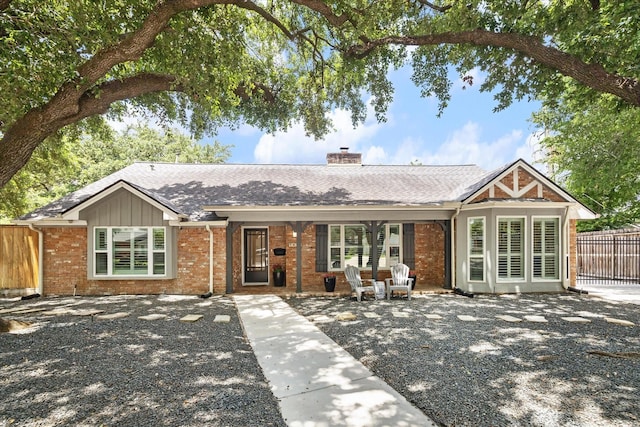 ranch-style house with fence, brick siding, roof with shingles, and a chimney