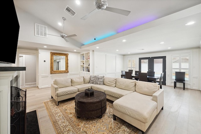 living area featuring vaulted ceiling, visible vents, and light wood finished floors