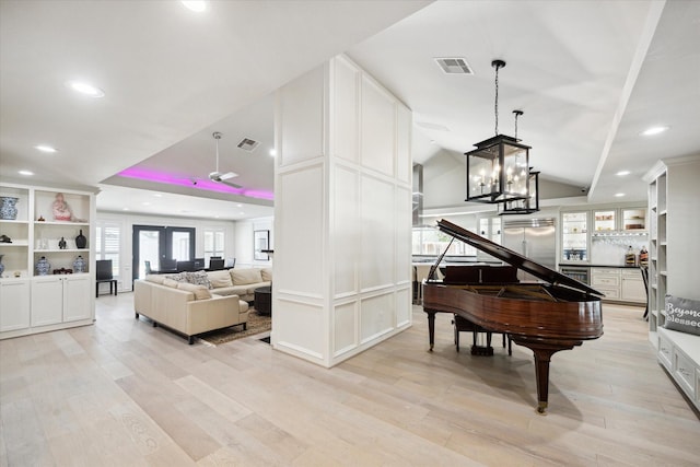 living area with lofted ceiling, visible vents, and light wood finished floors