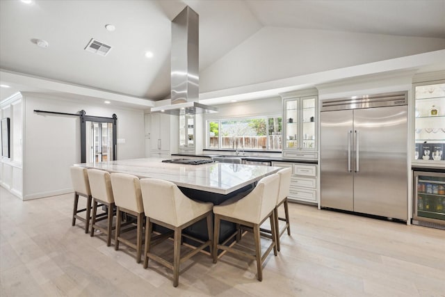 kitchen with visible vents, a barn door, wine cooler, appliances with stainless steel finishes, and island range hood