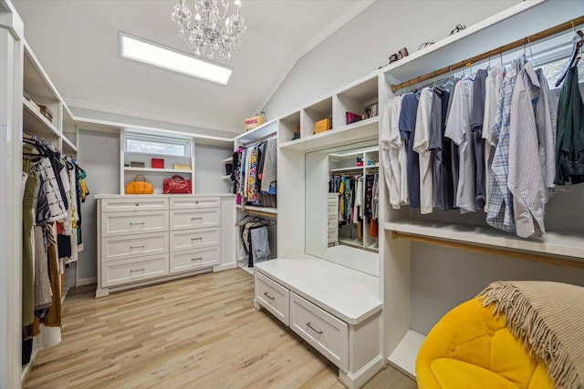 spacious closet featuring light wood-type flooring, an inviting chandelier, and vaulted ceiling