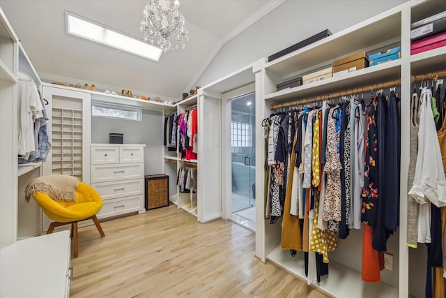 walk in closet featuring vaulted ceiling, a notable chandelier, and light wood-type flooring