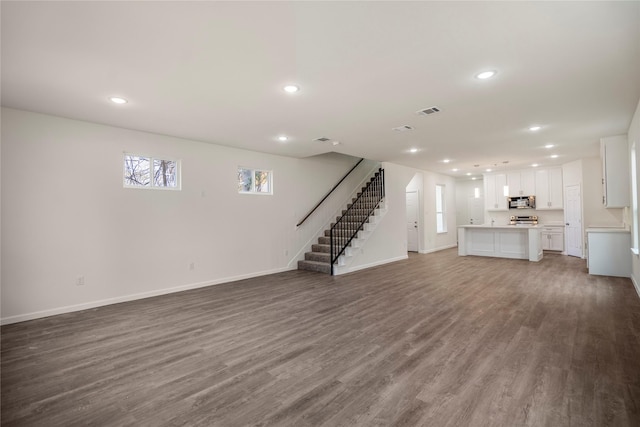 unfurnished living room with wood finished floors, visible vents, recessed lighting, stairs, and a wealth of natural light