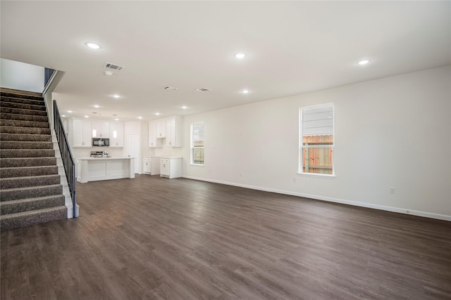 unfurnished living room featuring visible vents, baseboards, dark wood finished floors, stairs, and recessed lighting