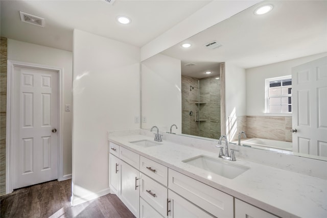 bathroom with visible vents, a stall shower, wood finished floors, and a sink