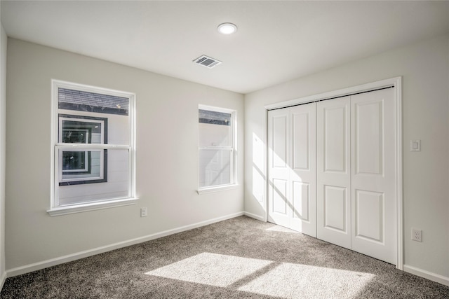 unfurnished bedroom featuring a closet, baseboards, visible vents, and carpet floors